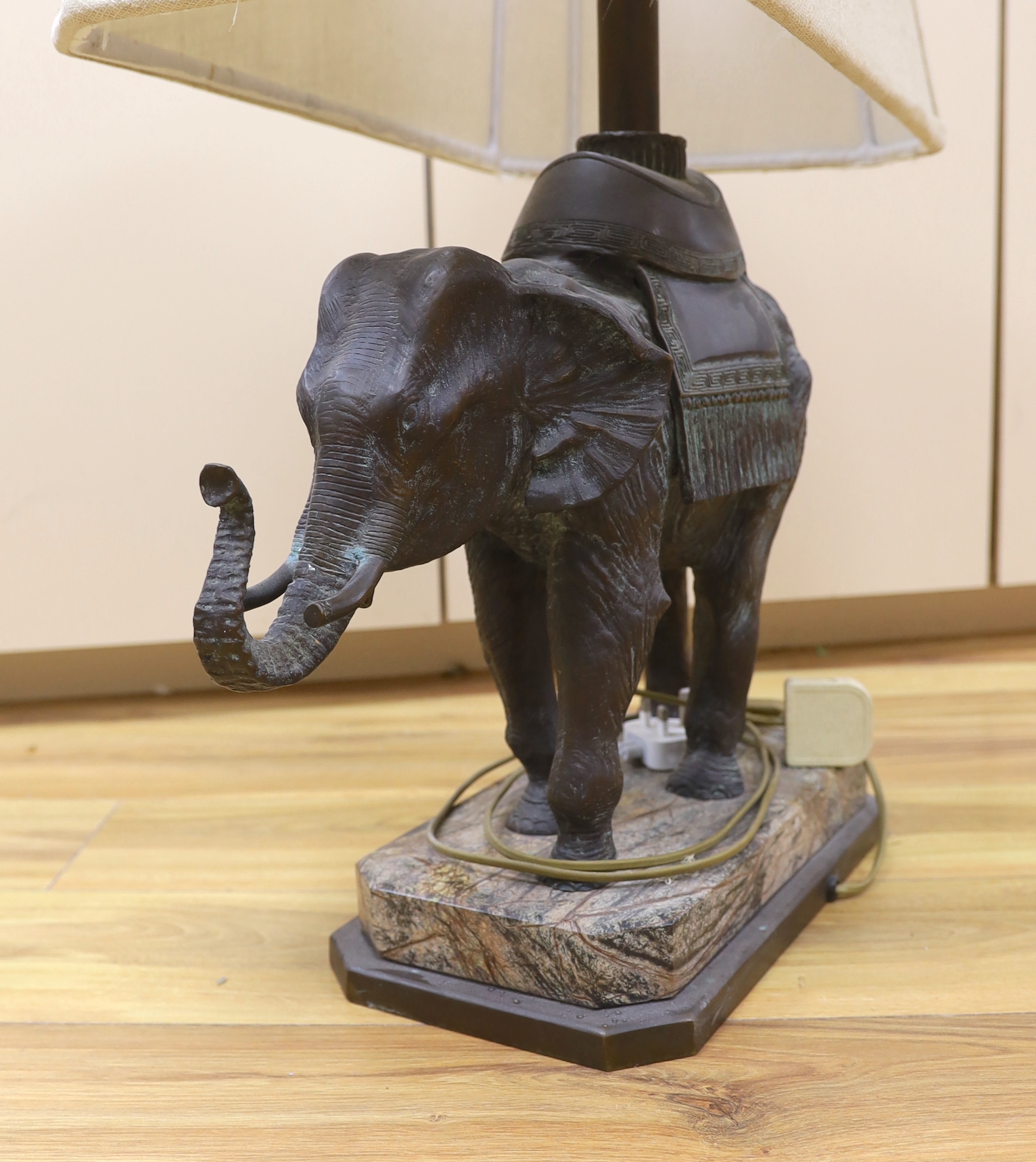 A bronzed elephant table lamp raised on shaped base, with shade, 79cm high